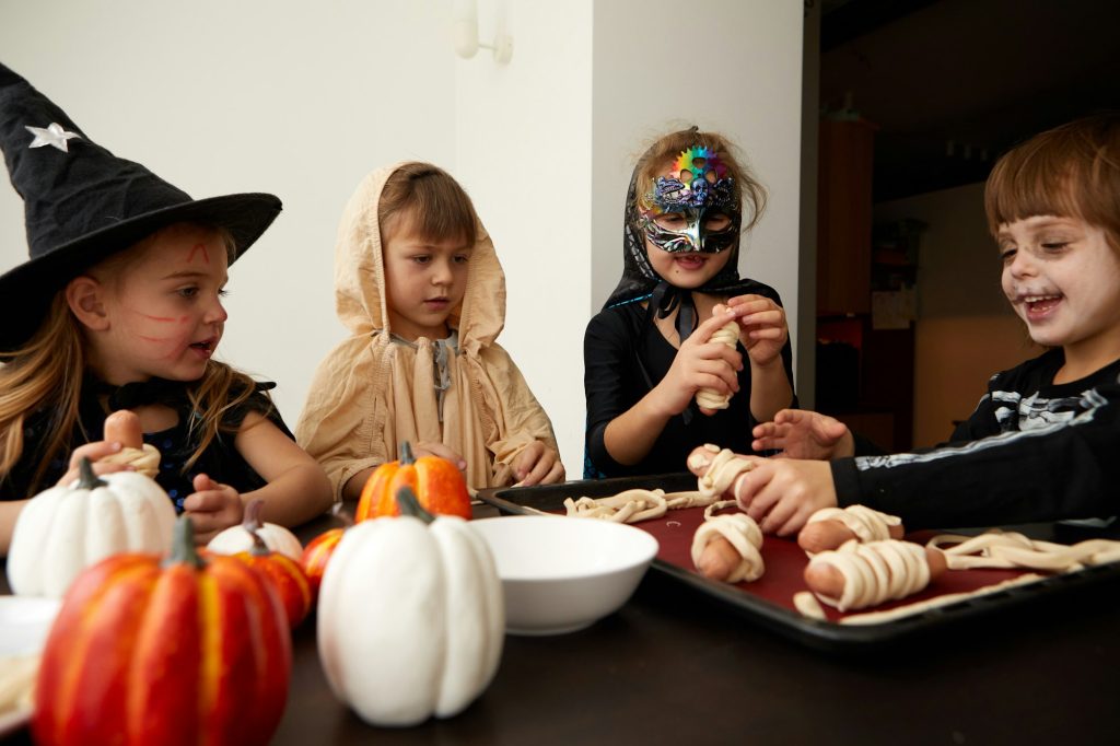 Children in Halloween costumes cooking together at table