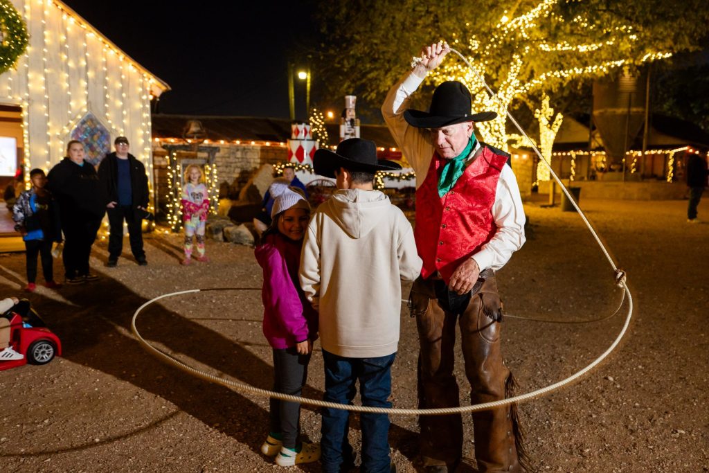Cowboy trick roper entertaining guests under the Christmas lights