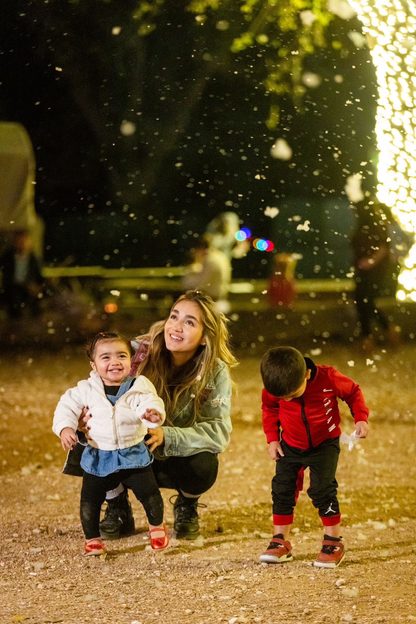 Mom and kids playing in falling snow at Old West Christmas Light Fest