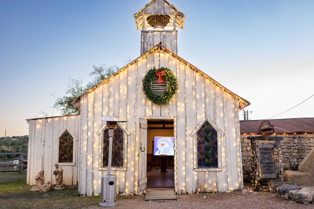 The Old West chapel decorated with Christmas lights and a wreath at Old West Christmas Light Fest