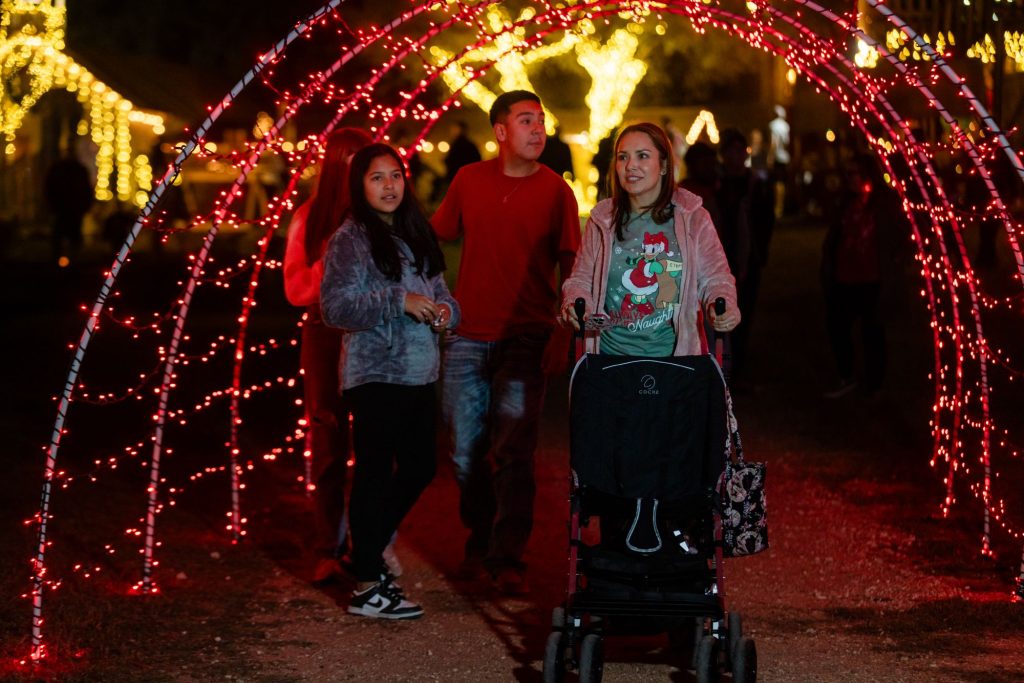 Family with a stroller walking through the Christmas light tunnels in Boerne, TX